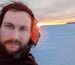 A man with a beard and ear muffs on an icy plain