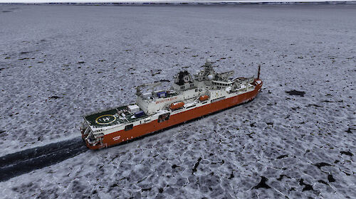 An aerial shot of a red and white icebreaker cutting a swathe through pancake ice