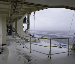 A ship's deck covered in snow, looking out to sea