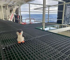 toy penguin on deck of ship