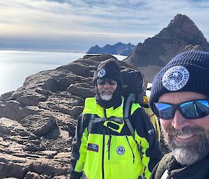 Two expeditioners standing on the top of a ridge, with icy plains below them