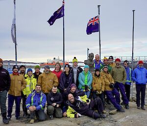 A group of expeditioners at Mawson station, standing outside in front of the station's flags