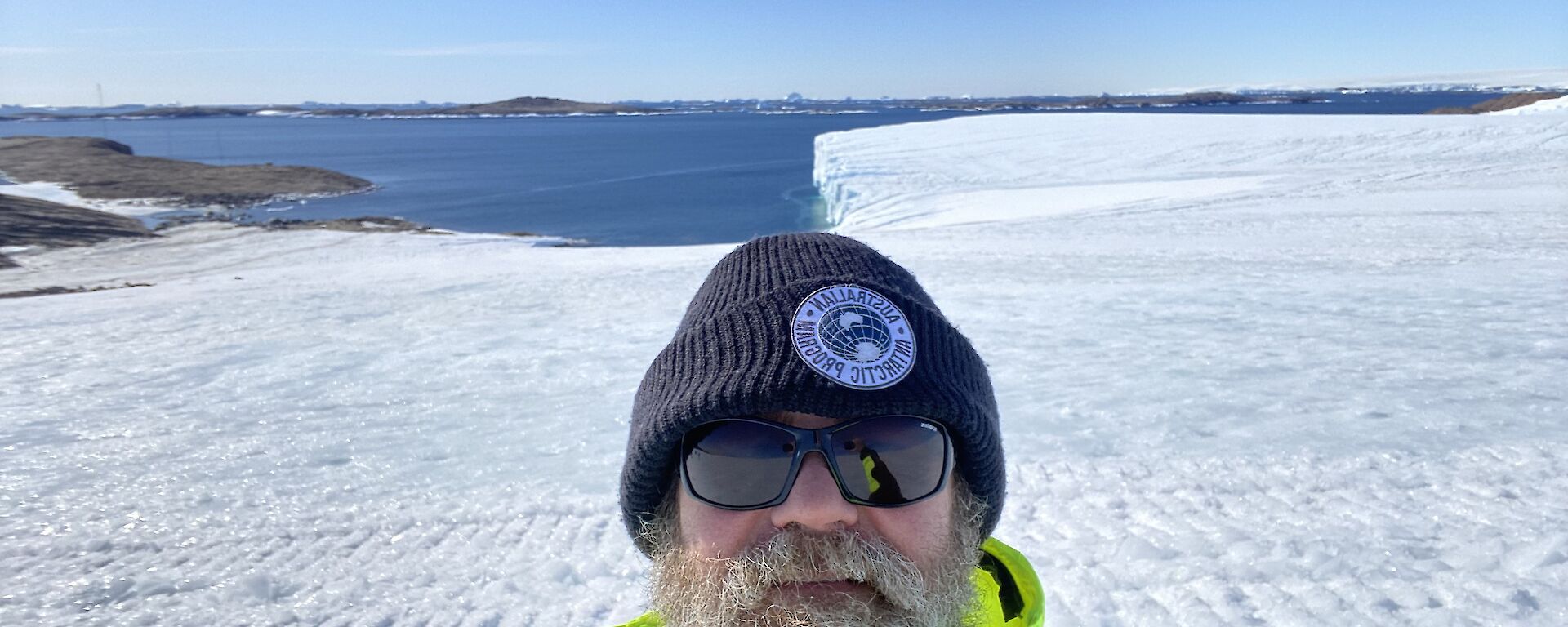 A man standing in front of an icy landscape, with the sea in the background