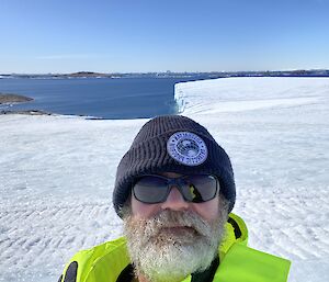 A man standing in front of an icy landscape, with the sea in the background