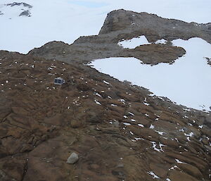 An aerial photograph of a small hut on the rocks