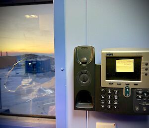 Photographs of a telephone on the wall next to a window with a sunset