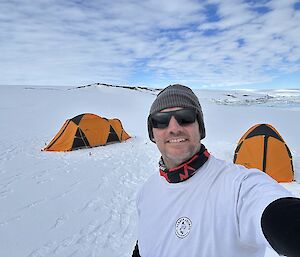 The author standing in front of two orange tents on the ice
