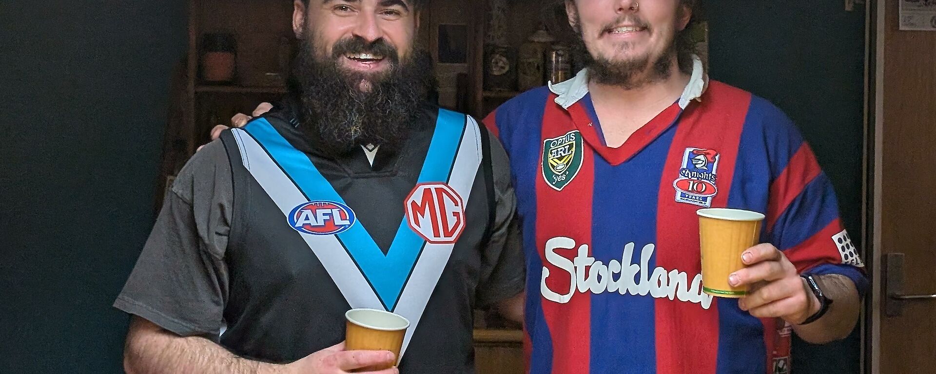 Two expeditioners, one in a sports jersey, with their arms around each other, smiling