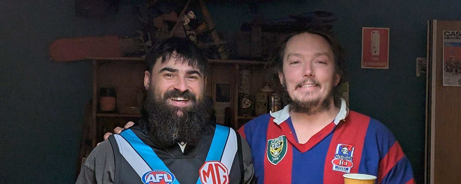 Two expeditioners, one in a sports jersey, with their arms around each other, smiling