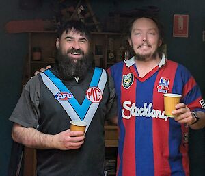 Two expeditioners, one in a sports jersey, with their arms around each other, smiling