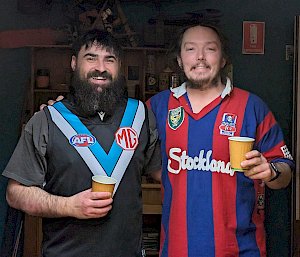 Two expeditioners, one in a sports jersey, with their arms around each other, smiling