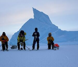 Five people standing on a flat ice surface with a jagged ice form behind them