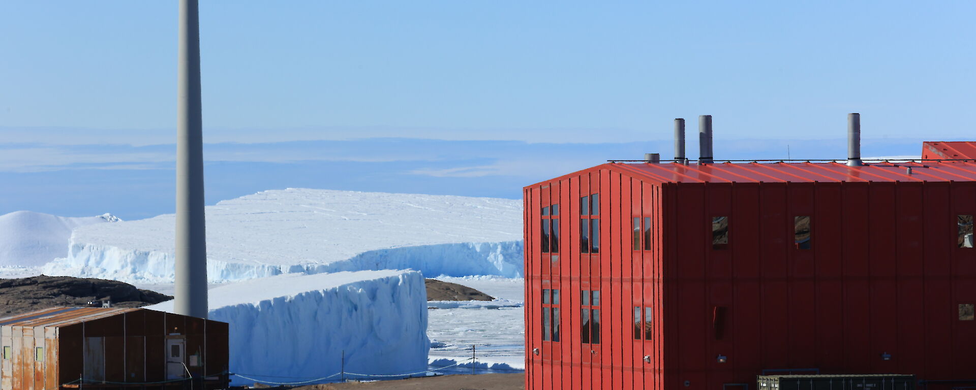A red shed with icebergs and snow in the background