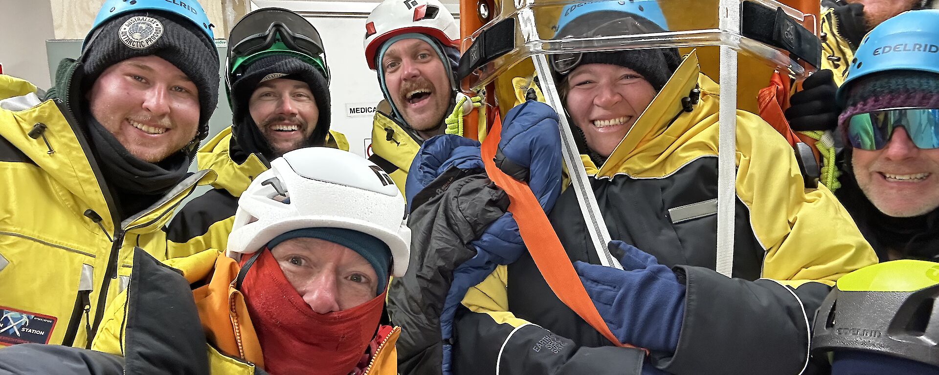 Eight people in yellow Antarctic clothing and helmets
