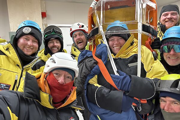 Eight people in yellow Antarctic clothing and helmets