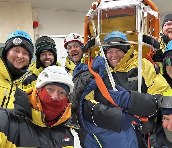Eight people in yellow Antarctic clothing and helmets