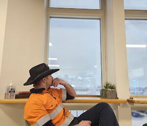 A Casey Station plumber deep in thought looking out a window to the ice capped background