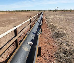 An open water channel running across a dry, red, flat landscape