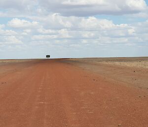 A flat red dirt landscape, with a single green tree on the horizon