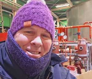 A man wearing many warm layers, including a woolen beanie, neckwarmer and thick jacket.