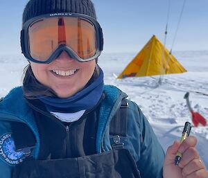 An expeditioner at a deep field camp in Antarctica, with a yellow tent in the background.