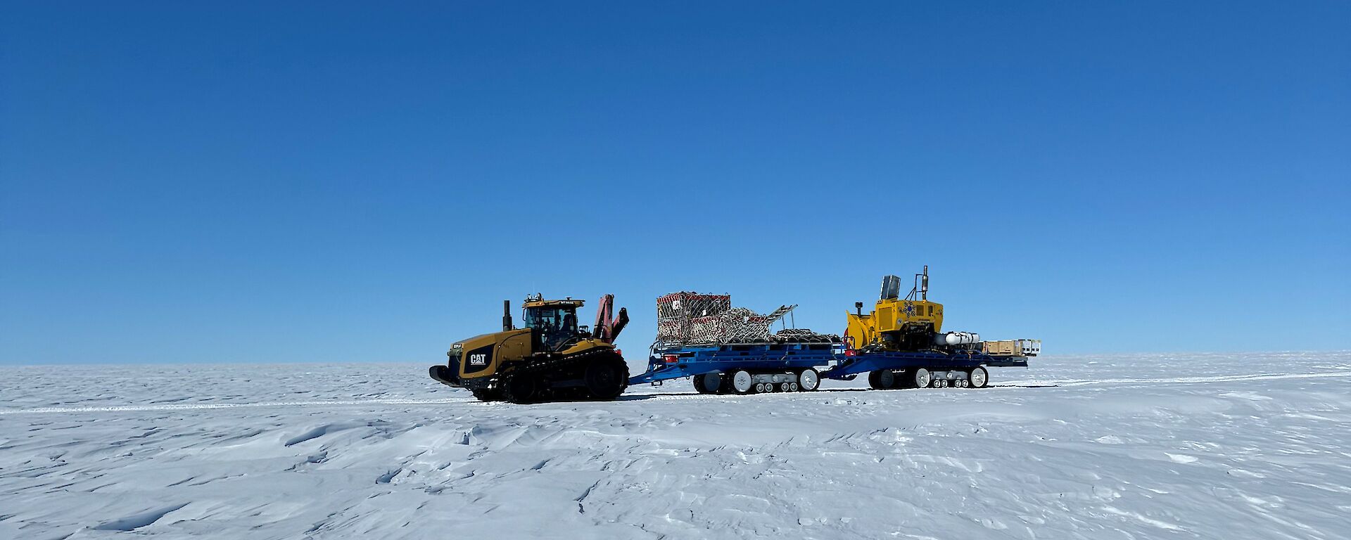 Three pieces of heavy machinery in a convoy on their way to the ice runway