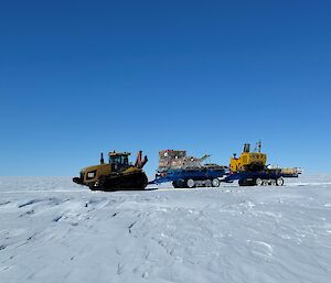 Three pieces of heavy machinery in a convoy on their way to the ice runway