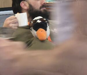 The goose sitting next to an expeditioner who is sitting down