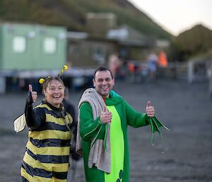 A women in a bumblebee costume and a man in a Kermit the frog costume give a thumbs up after taking a swim.