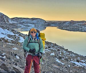 person standing on hill next to lake