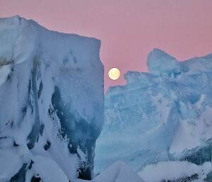 moon in background with icebergs infront