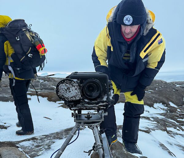 Expeditioners outside with a large camera on a tripod