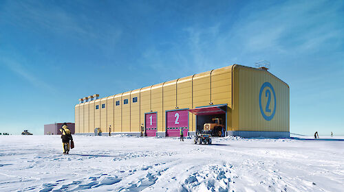 A bright yellow building on the ice under a blue sky
