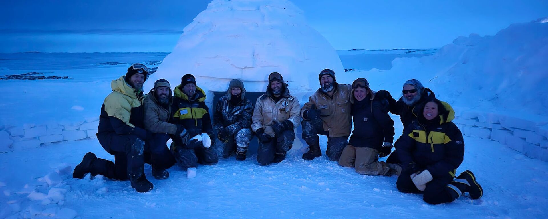 Expeditioners standing in front of the igloo they built