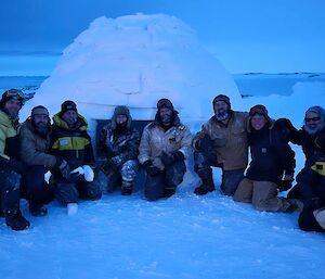 Expeditioners standing in front of the igloo they built