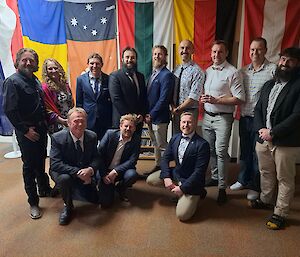 The Casey infrastructure team dressed up standing in front of flags at the midwinter dinner