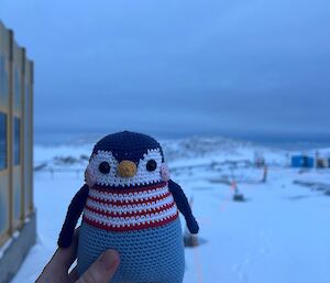 A crochet penguin with a snow background
