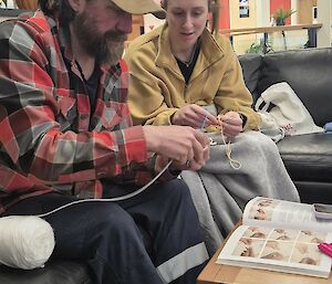 An expeditioner learning crochet from another expeditioner