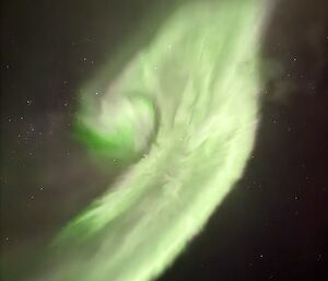 A bright lime and fluorescent green swirl of light in the night sky.
