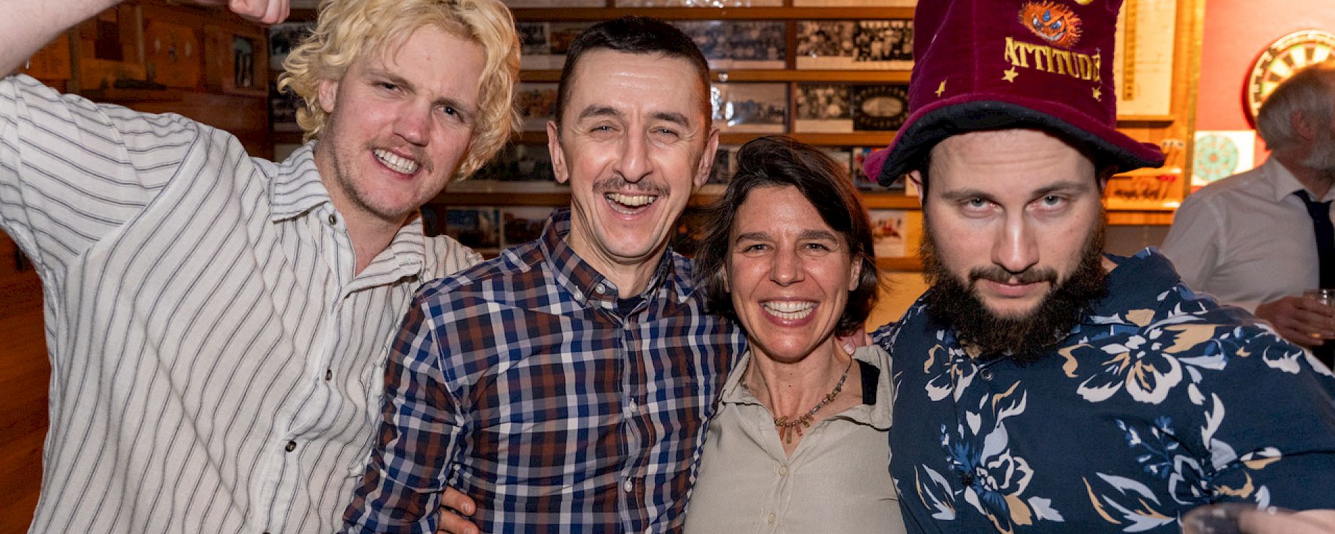 Four people stand close together smiling.