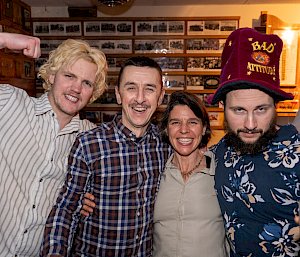 Four people stand close together smiling.