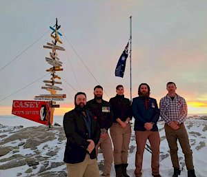 The five Wilkins Team expeditioners dressed nicely standing in front of the Casey sign in the snow on ANZAC Day