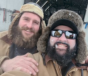 Two expeditioners with their beards smiling outdoors