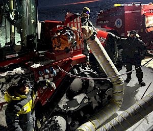 Two expeditioners standing next to a big red tractor