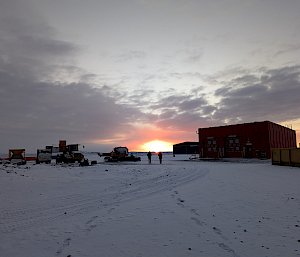 people walking toward sunrise with building in background