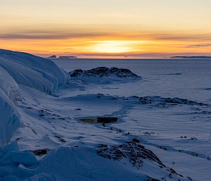 A sunset behind a huddle of emperor penguins at Taylor Glacier.
