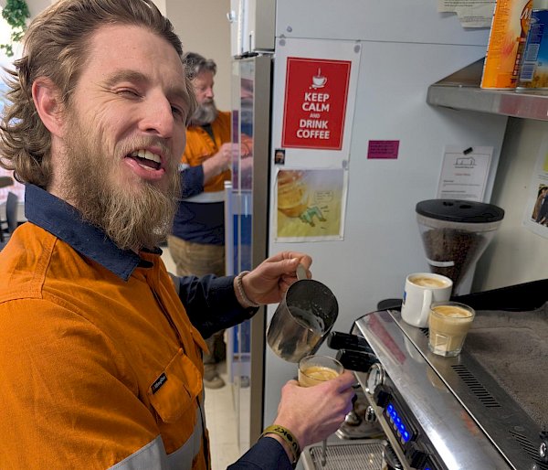 A man creates latte art on the top of a third coffee