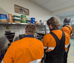 Three men in high vis shirts standing at the station's coffee machine
