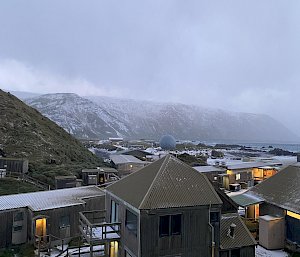 Snow covered buildings in the forground and snow covered hills in the distance
