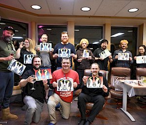 A group of expeditioners show off their paintings of emperor penguins